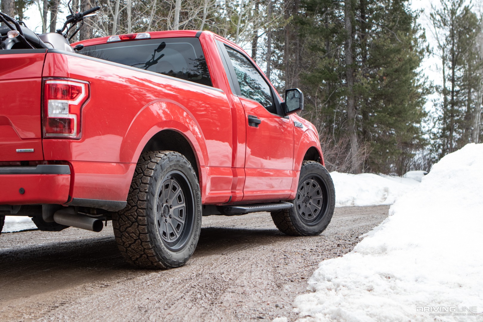 Nitto Recon Grappler A/T Tires on a Ford F150 with a motorcycle in the bed on snow muddy road