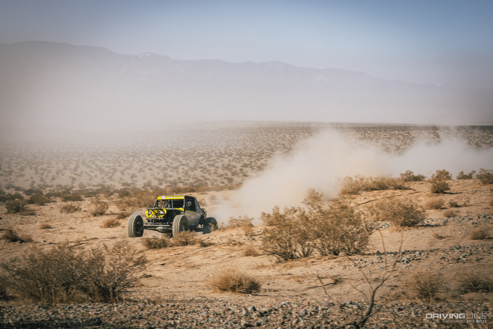 Erik Miller drives across the desert with a dust trail in his wake