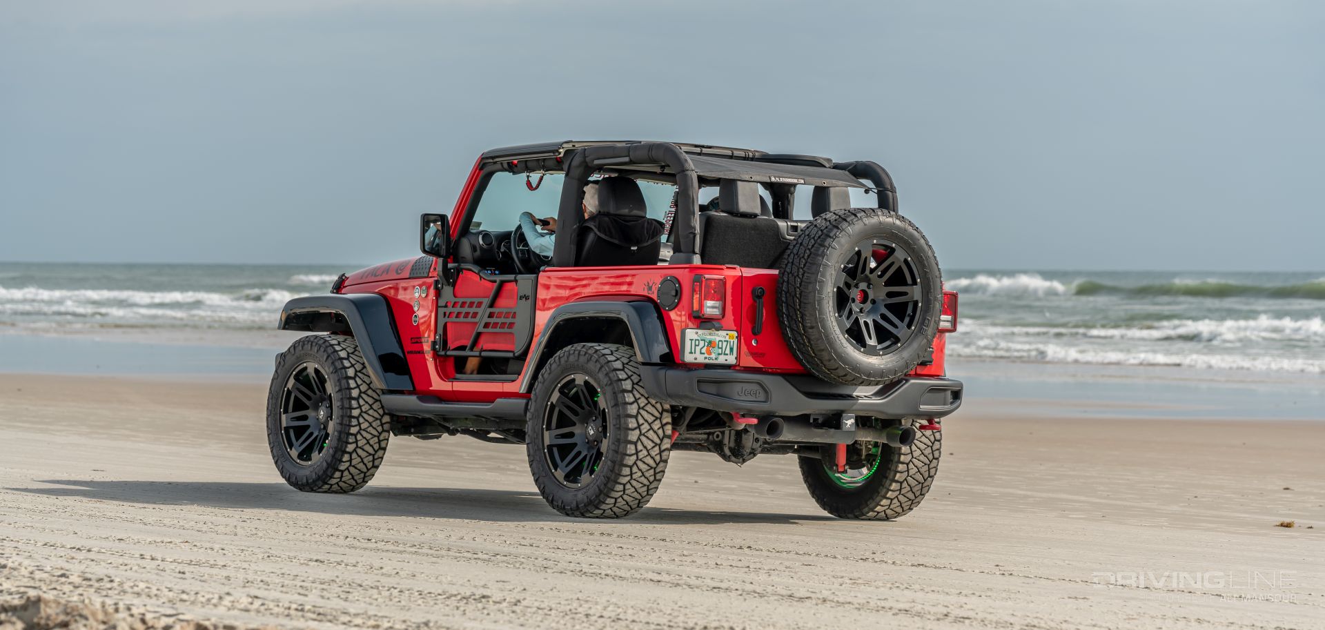 Red Jeep Wrangler JK on Nitto Ridge Grapplers driving on Daytona Beach