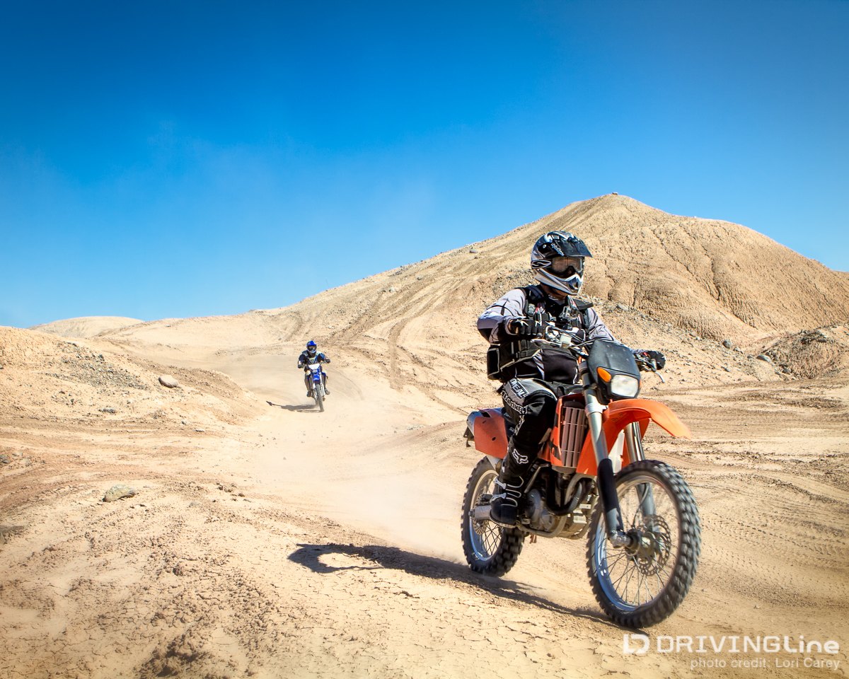 Two dirt bikes driving through dirt hills