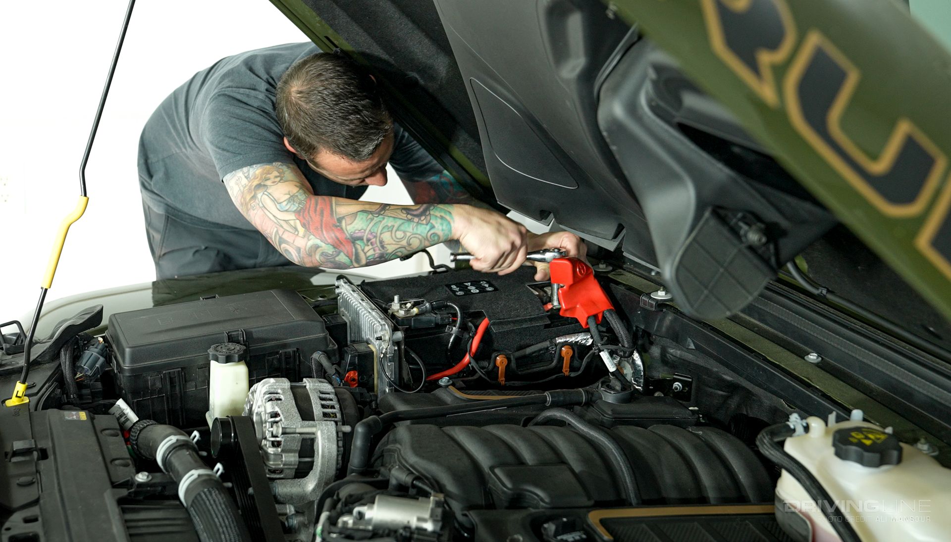 Ali Mansour under the hood of a jeep working on a battery